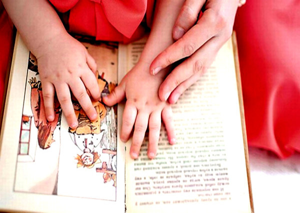 Foto de mãos adultas e infantis sobre um livro
